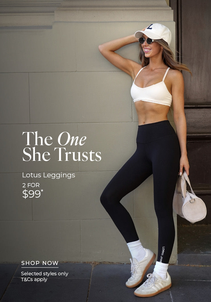 Woman leaning against a sage-green wall in black Lotus Leggings, a white sports bra, white cap, sunglasses, white crew socks and sneakers, holding a small cream duffle bag. Text: The One She Trust. Lotus Leggings 2 for $99* Selected styles only. T&Cs apply - Shop Now