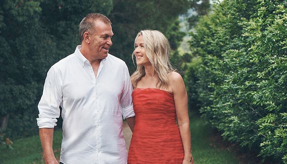 Lorna Jane Clarkson wearing a red strapless dress, alongside Bill Clarkson wearing a white button up shirt