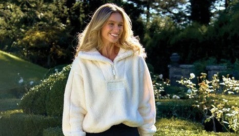 Model wearing a white zip jacket standing in a garden