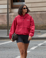 Model wearing a red jacket and blue bike shorts