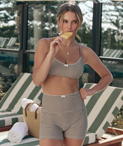 Model wearing a black and white check sports bra and bike shorts, eating an ice block