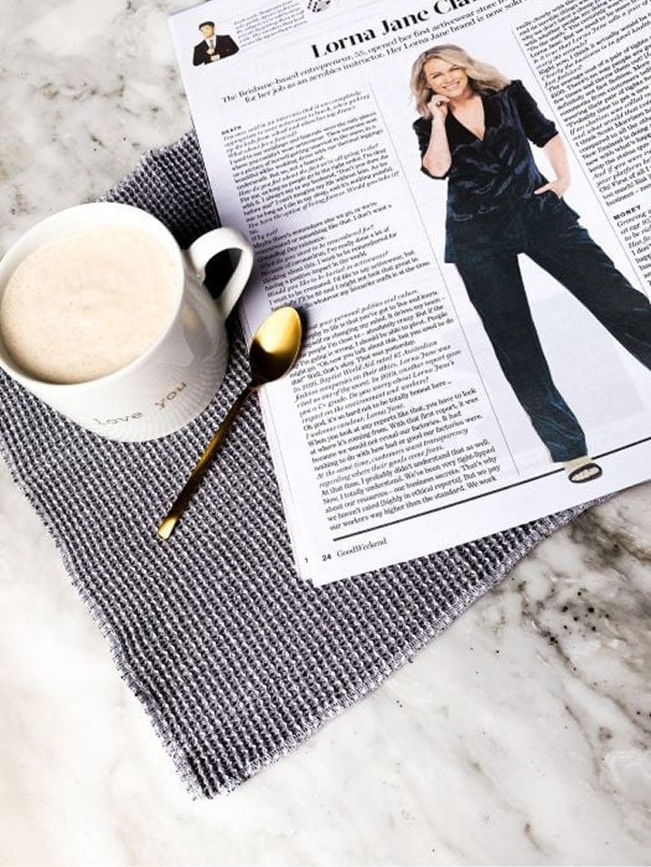 A Good Weekend magazine feature on Lorna Jane Clarkson lying on a grey woven placemat beside a mug of coffee and a gold spoon on a marble surface.