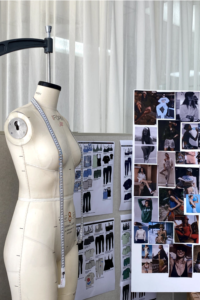 A Lorna Jane design studio with a dress form, garment tech sketches, and a mood board of activewear campaign imagery.