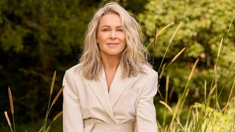 Lorna Jane Clarkson wearing a beige jacket sitting in a field with long grass