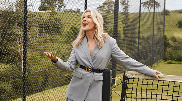 Lorna Jane Clarkson wearing a grey blazer with black belt on tennis court