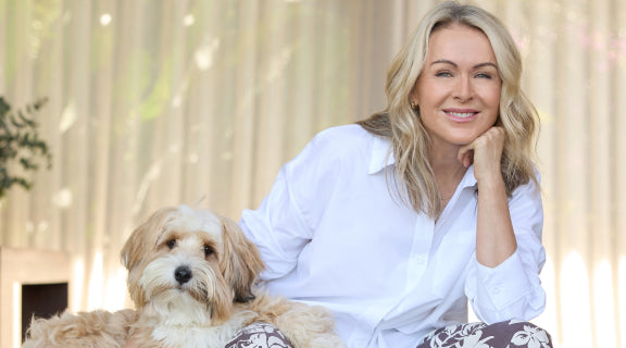 Lorna Jane Clarkson wearing a white long sleeve button up shirt with a caramel coloured dog