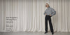 A woman in black All Day Active Midrise Pants styled with an oversized grey checked zip-up jacket, sunglasses and black loafers, against a soft neutral curtain backdrop.
Text: Your Wardrobe's Missing Piece. All Day Active Midrise Pants. Take $20 Off* T&Cs apply - Shop Now