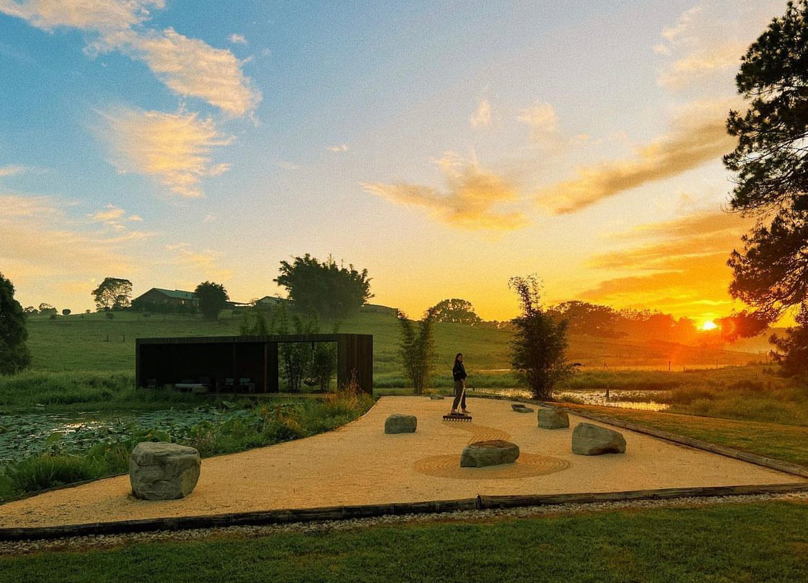 Sand meditation garden with someone making a pattern in the sand. Sunset. 