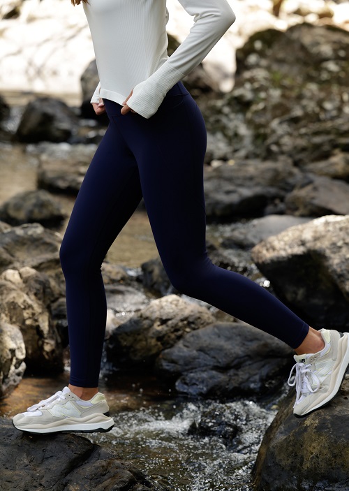 woman wearing a white long sleeve top and full length navy blue thermal leggings