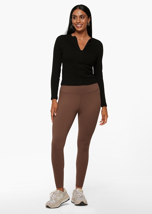 woman wearing chocolate brown full length thermal tights and a black zip up long sleeve top