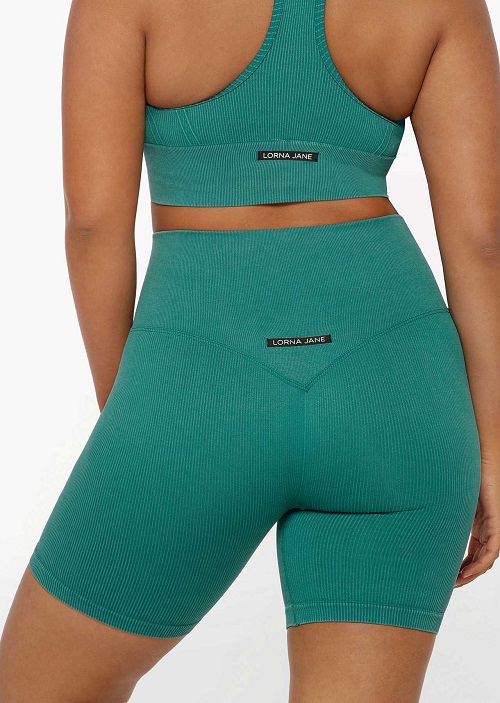 Back image of a woman wearing matching bike shorts and sports bra in washed dark teal colour