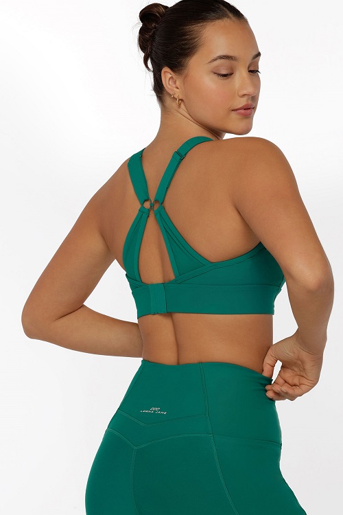 brunette woman wearing clasp back teal green sports bra and tights