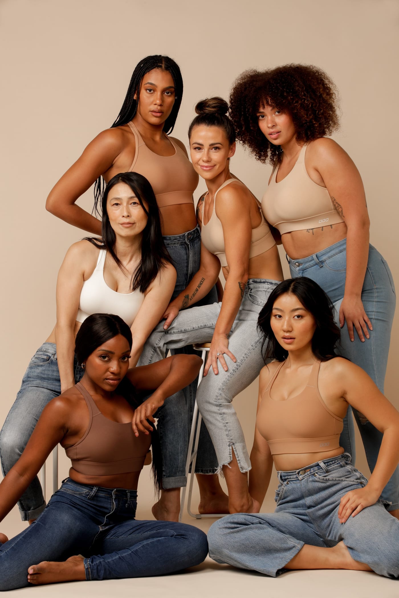 A group of models wearing Compress & Compact Sports Bras and jeans.